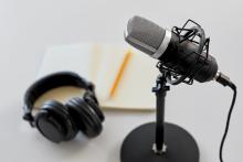 A podcast microphone, headphones, and notebook.